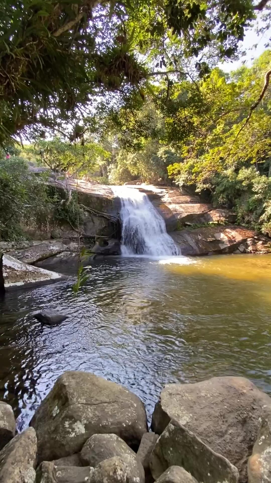 Queda d'água caindo num poço cercado de pedras na Cachoeira do Prumirim