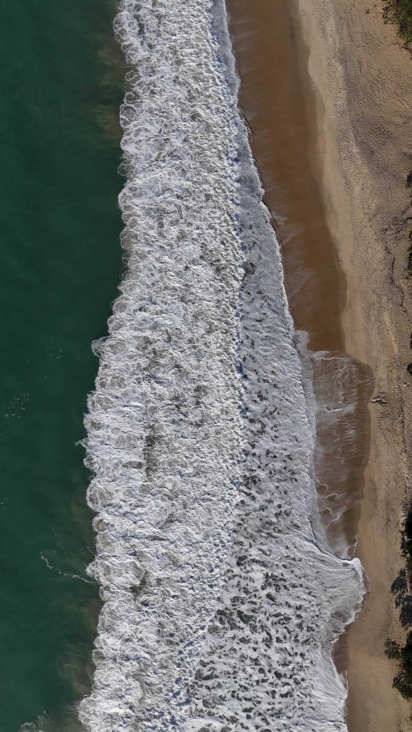 Mar visto de cima com faixas de espuma