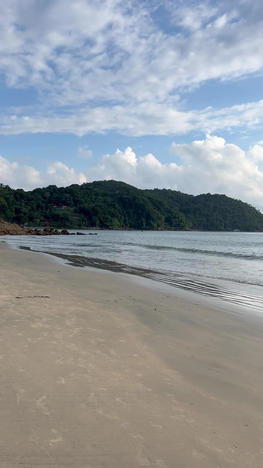 Areia larga e mar calmo da Praia da Almada com morro de mata ao fundo