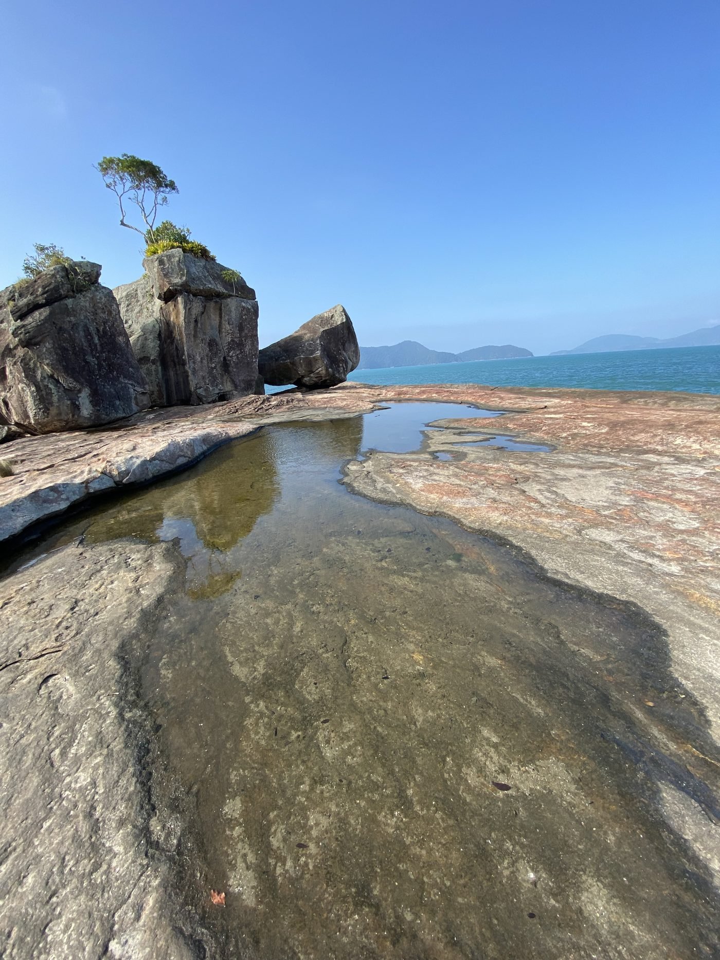 Costão de pedra molhada com poça de água no Pontão da Fortaleza