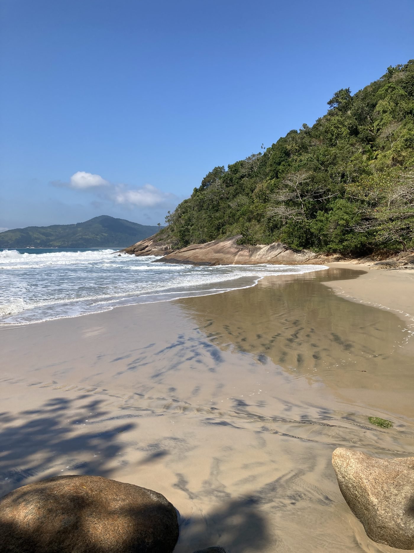 Praia de Fora em Ubatuba com areia vazia, costão de mata e mar de ondas pequenas