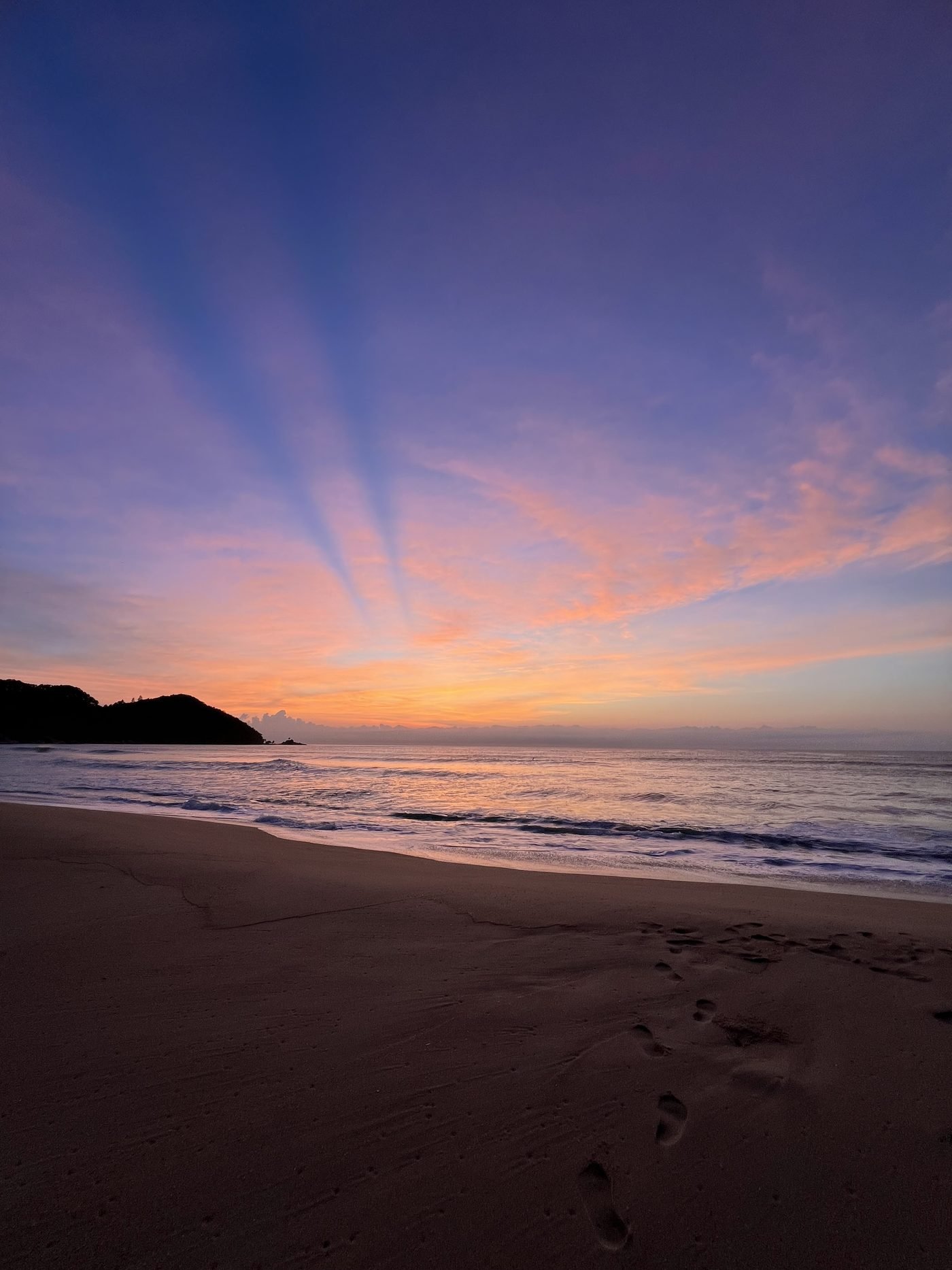 Céu rosa e laranja com raios de luz antes do sol nascer na Praia Vermelha do Centro