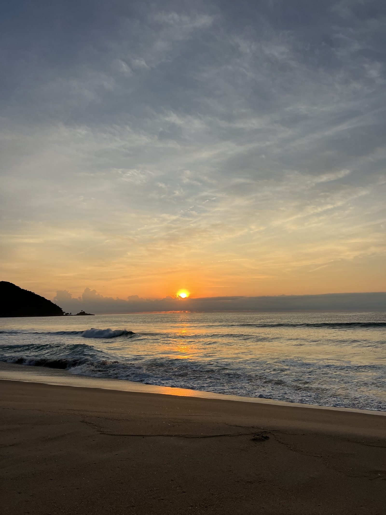Sol nascendo sobre o mar na Praia Vermelha do Centro, em Ubatuba, com a luz dourada refletida na água