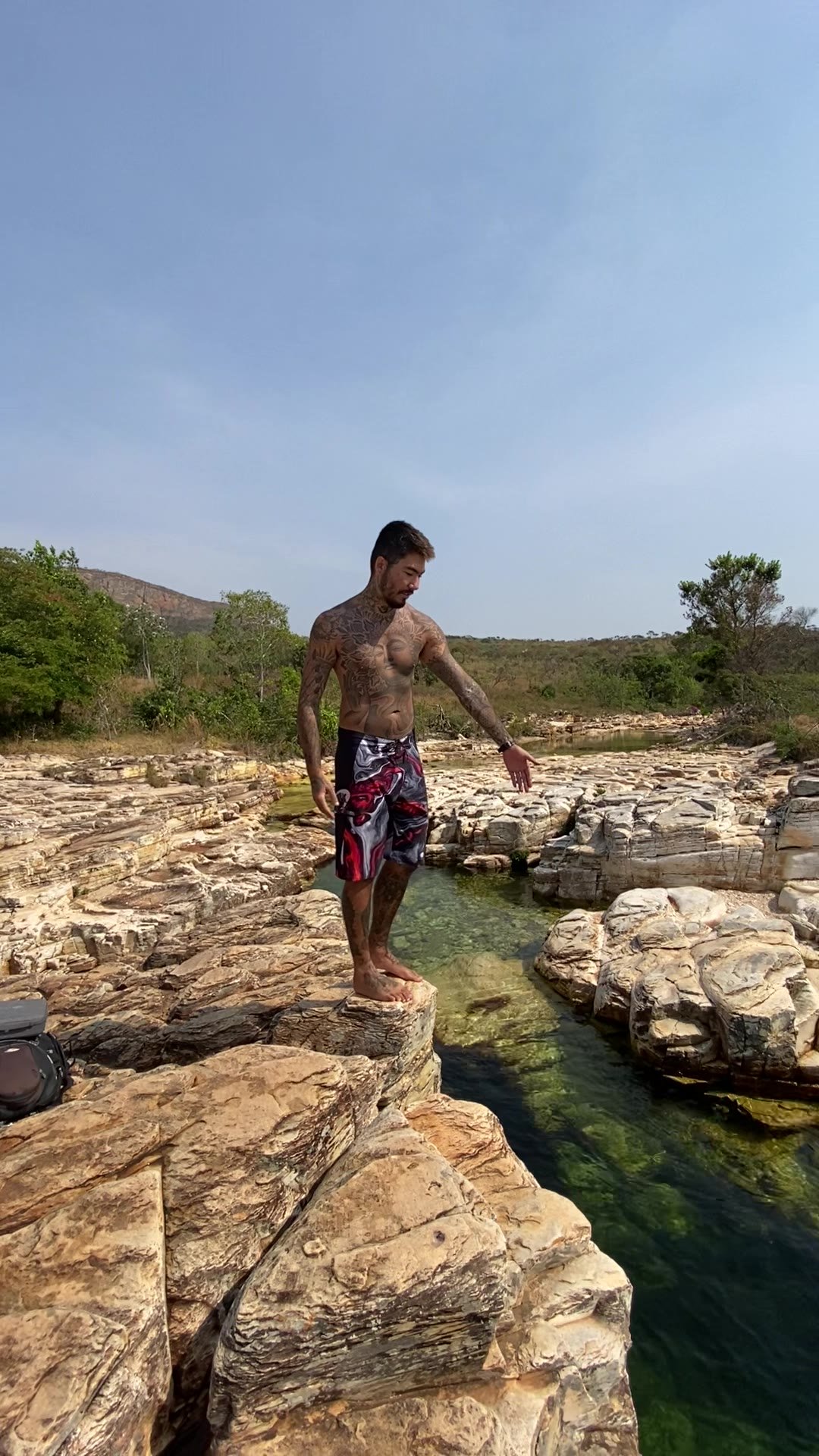 Renan na laje de pedra sobre um poço verde do Ribeirão Quebra Anzol