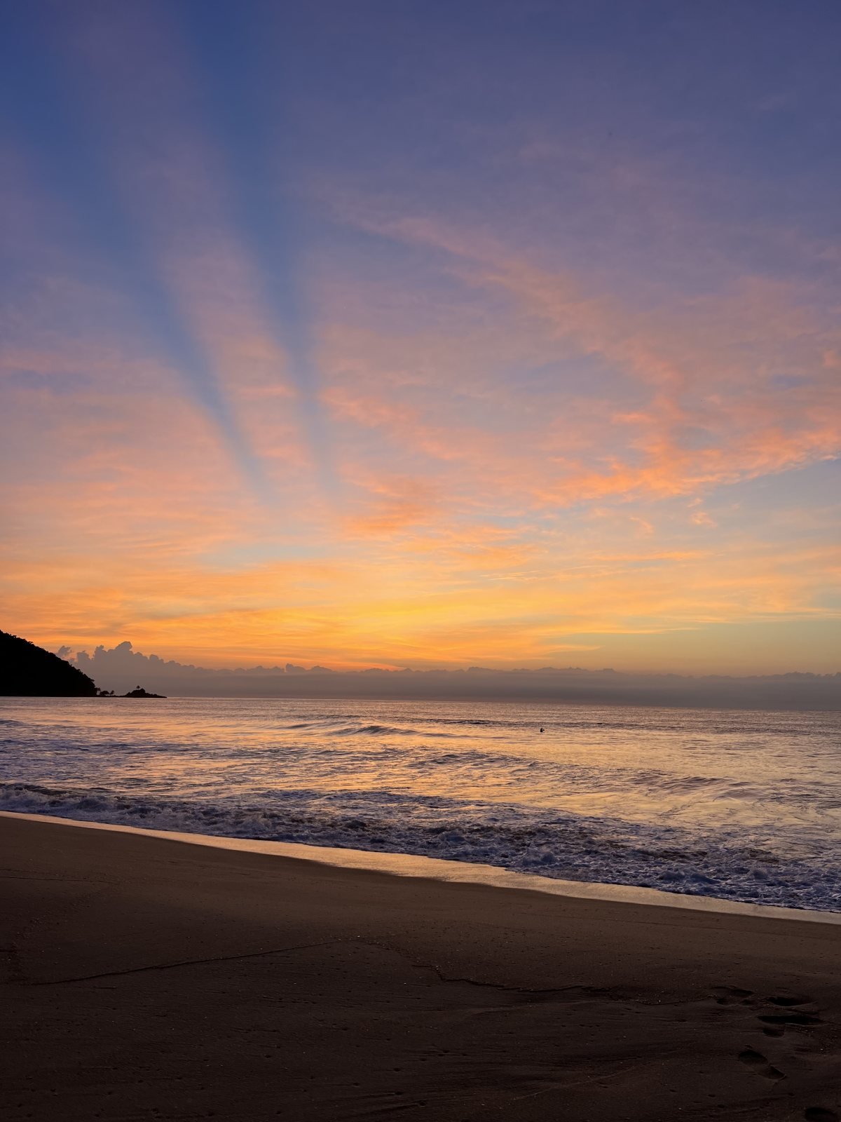 Céu rosa e raios de luz antes do sol nascer na Praia Vermelha do Centro, Ubatuba