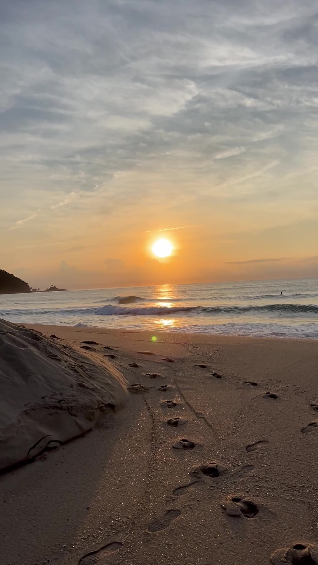 Sol nascendo no mar com pegadas na areia vazia da Praia Vermelha do Centro