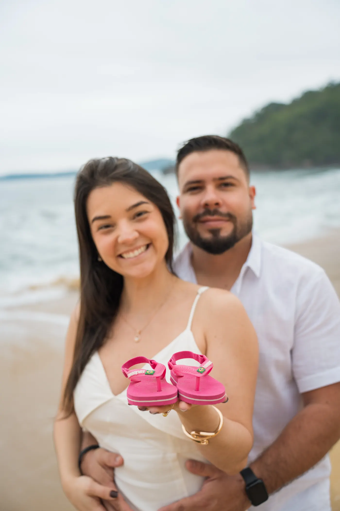 Casal mostrando o chinelinho do bebê pra câmera — foto autoral de Renan Life, Ubatuba