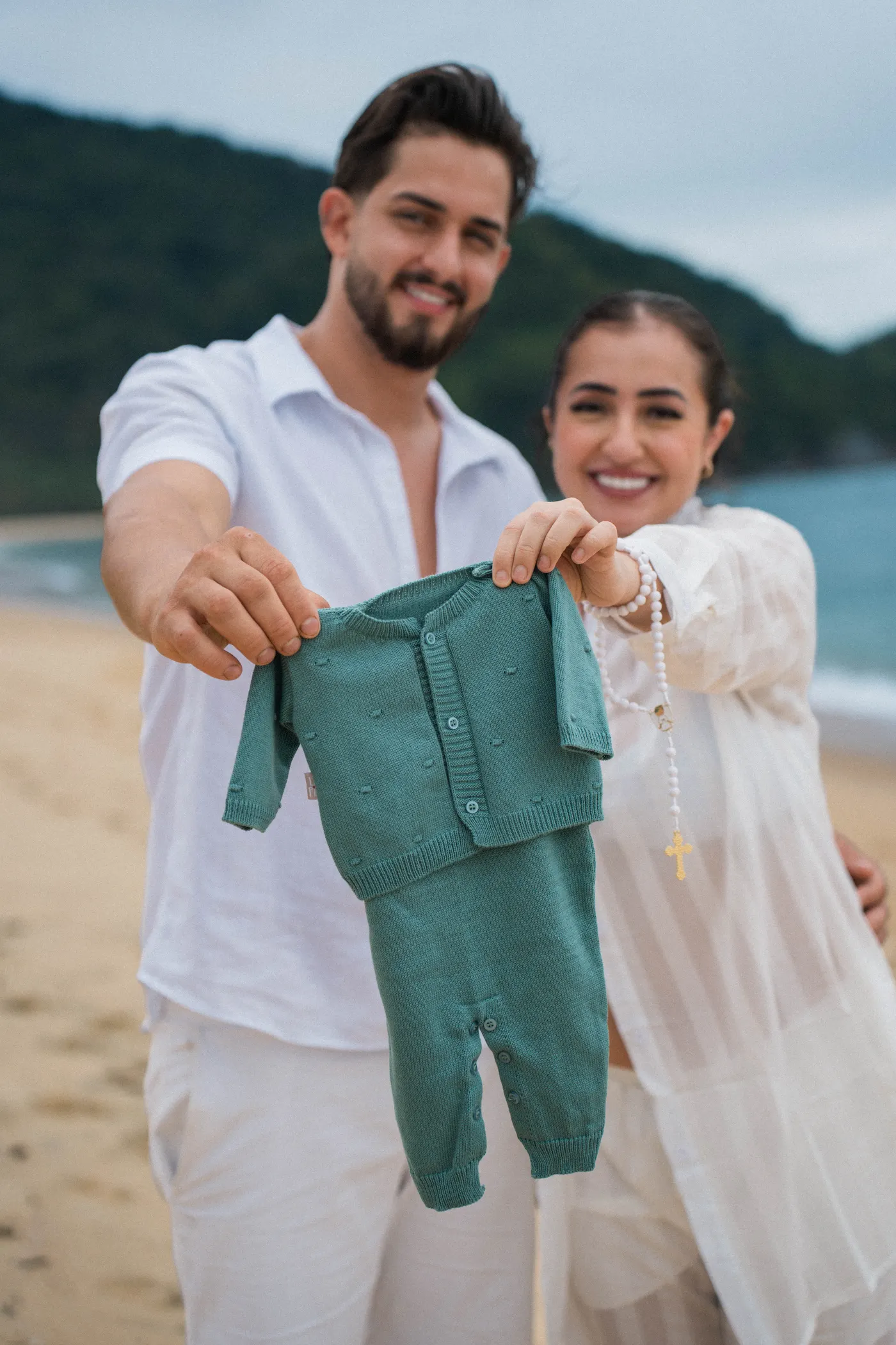 Casal segurando a roupinha do bebê pra câmera — foto autoral de Renan Life, Ubatuba