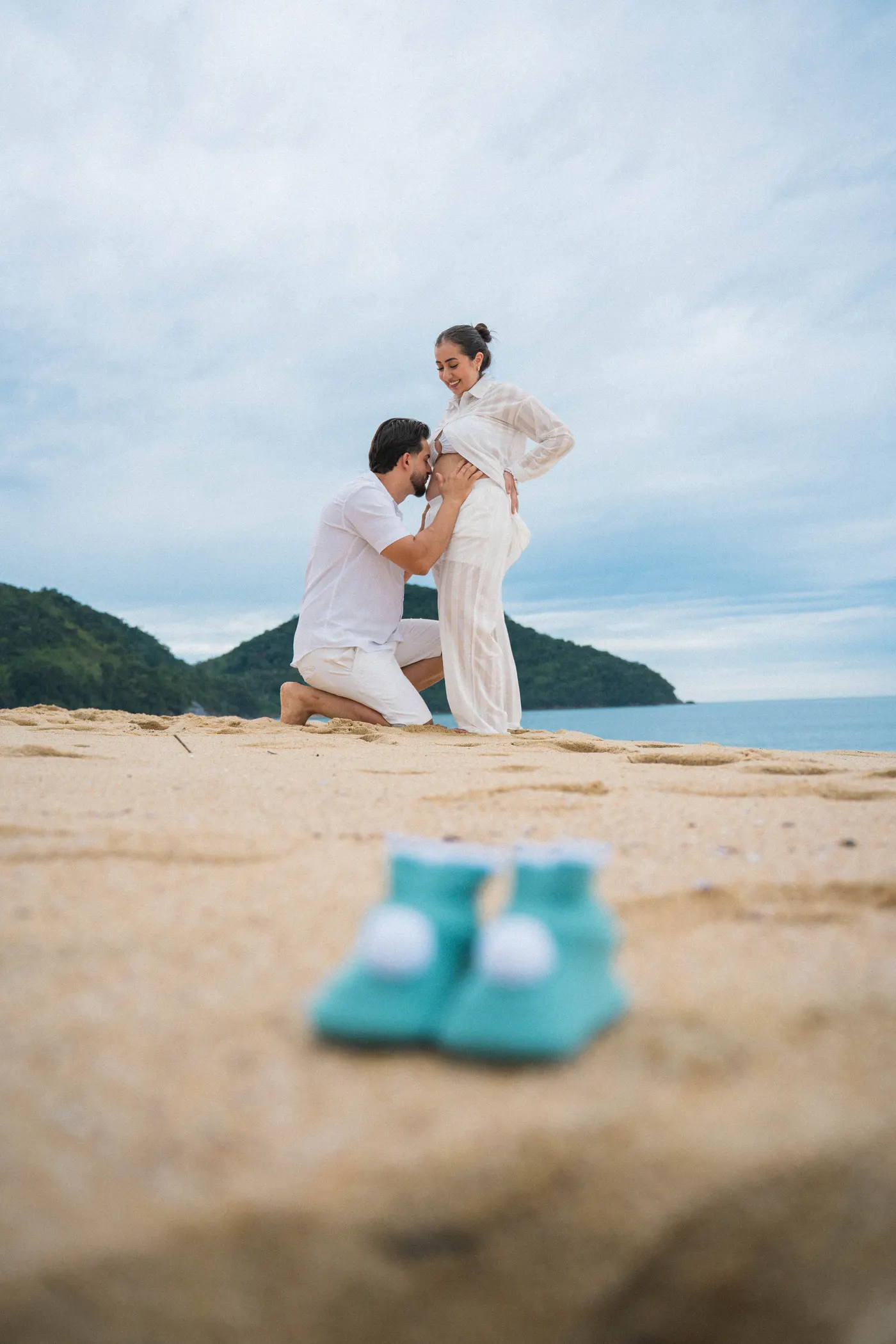 Sapatinhos do bebê em primeiro plano e o casal ao fundo — foto autoral de Renan Life, Ubatuba