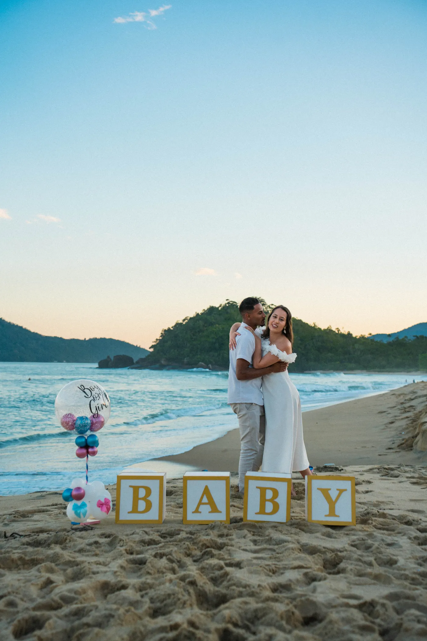 Cubos BABY na areia com o casal abraçado ao fundo — foto autoral de Renan Life, Ubatuba