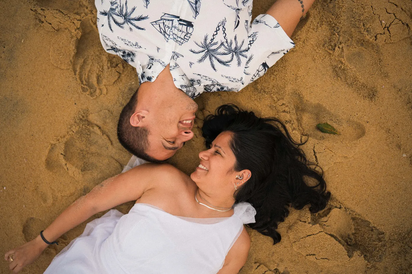Casal deitado na areia com as cabeças encostadas, visto de cima — foto autoral de Renan Life, Ubatuba