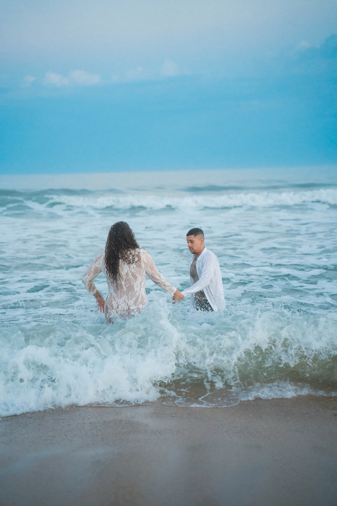 Casal correndo de mãos dadas pra dentro do mar — foto autoral de Renan Life, Ubatuba