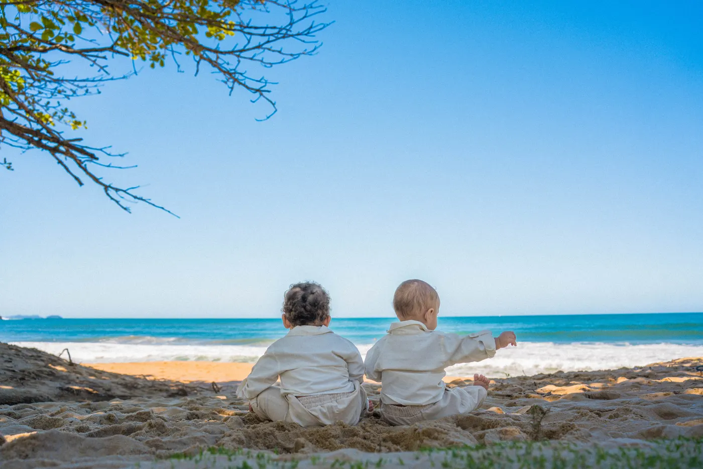 Duas crianças sentadas de costas olhando o mar — foto autoral de Renan Life, Ubatuba