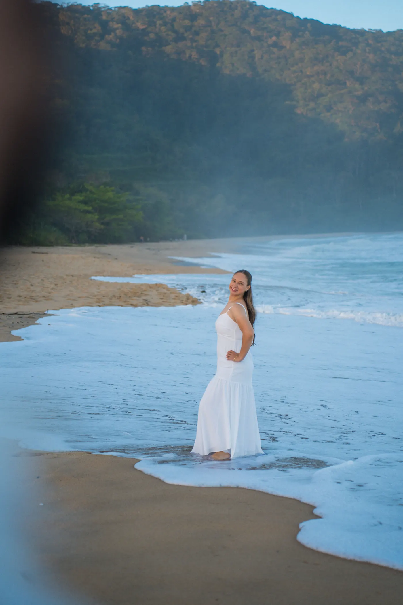Mulher de vestido branco na beira do mar olhando pra câmera — foto autoral de Renan Life, Ubatuba