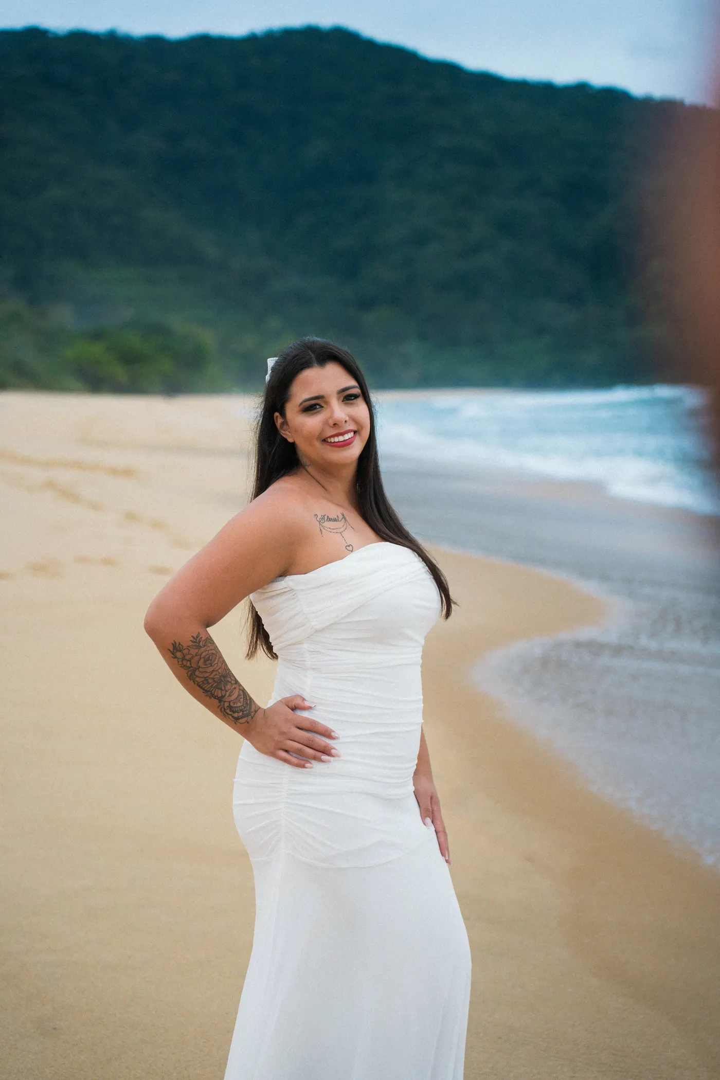 Mulher de vestido branco com a mão na cintura na beira da praia — foto autoral de Renan Life, Ubatuba