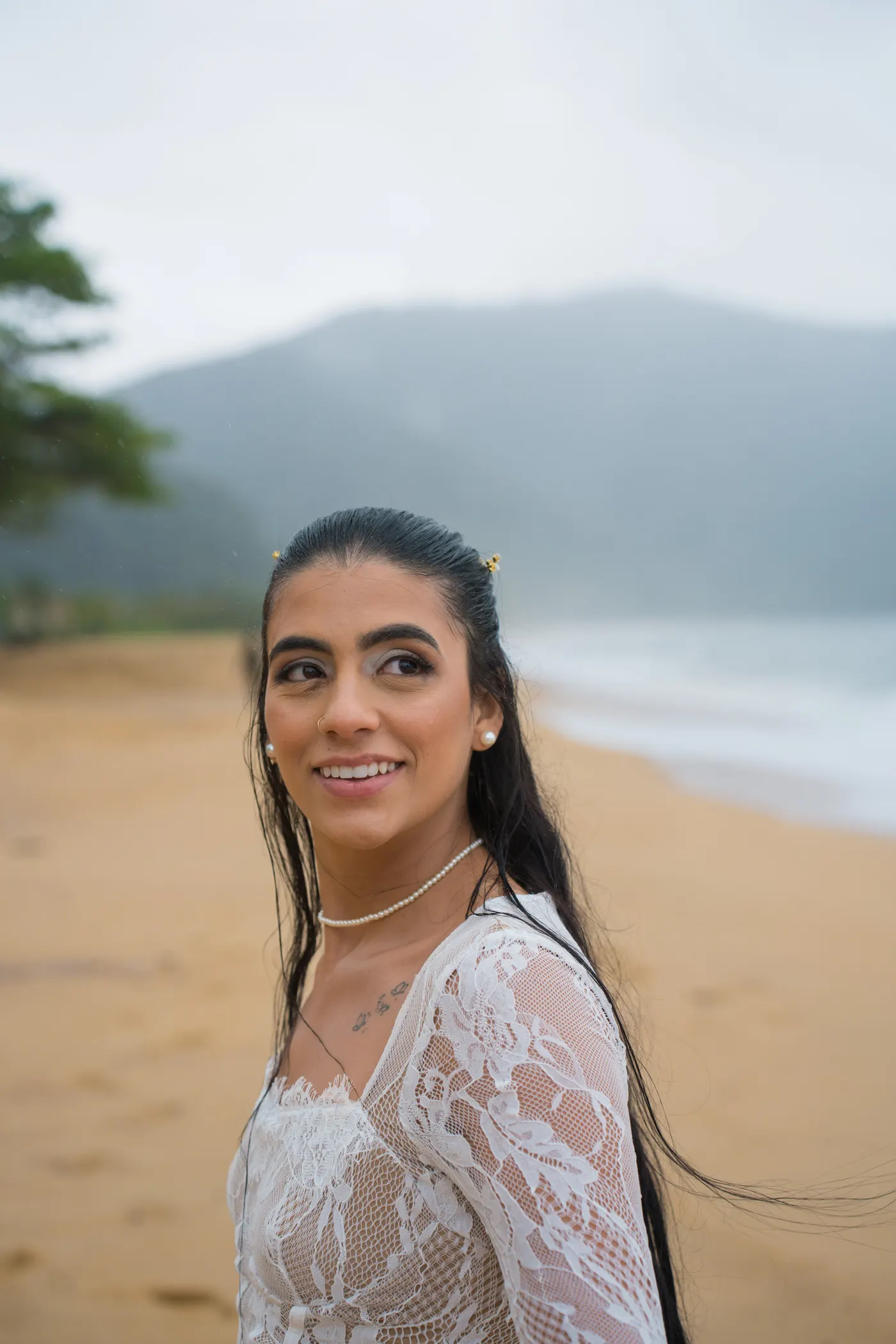 Retrato de perto, mulher olhando pro lado com o mar desfocado ao fundo — foto autoral de Renan Life, Ubatuba