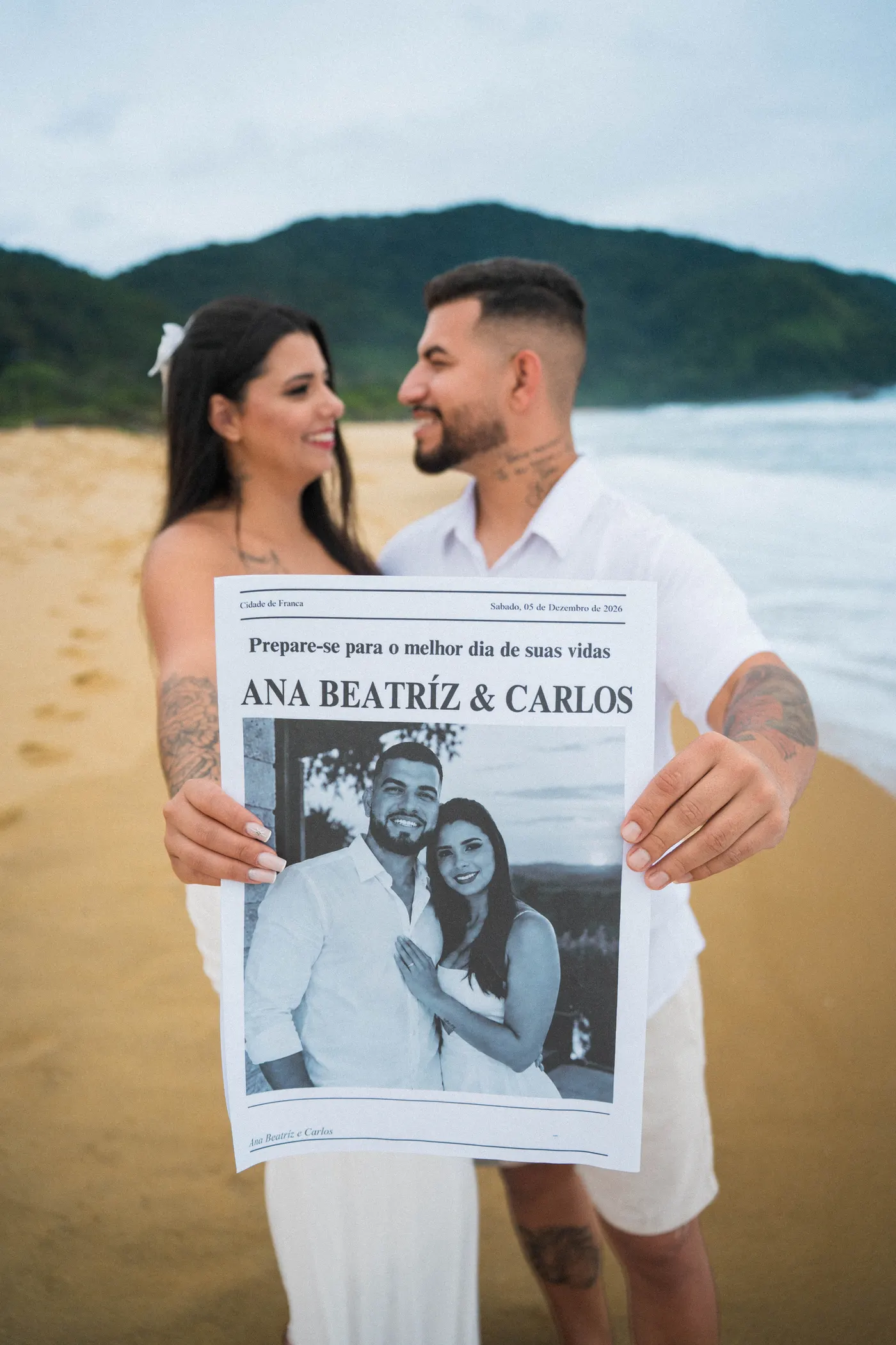 Noivos mostrando o jornal do save the date com os nomes e a data — foto autoral de Renan Life, Ubatuba