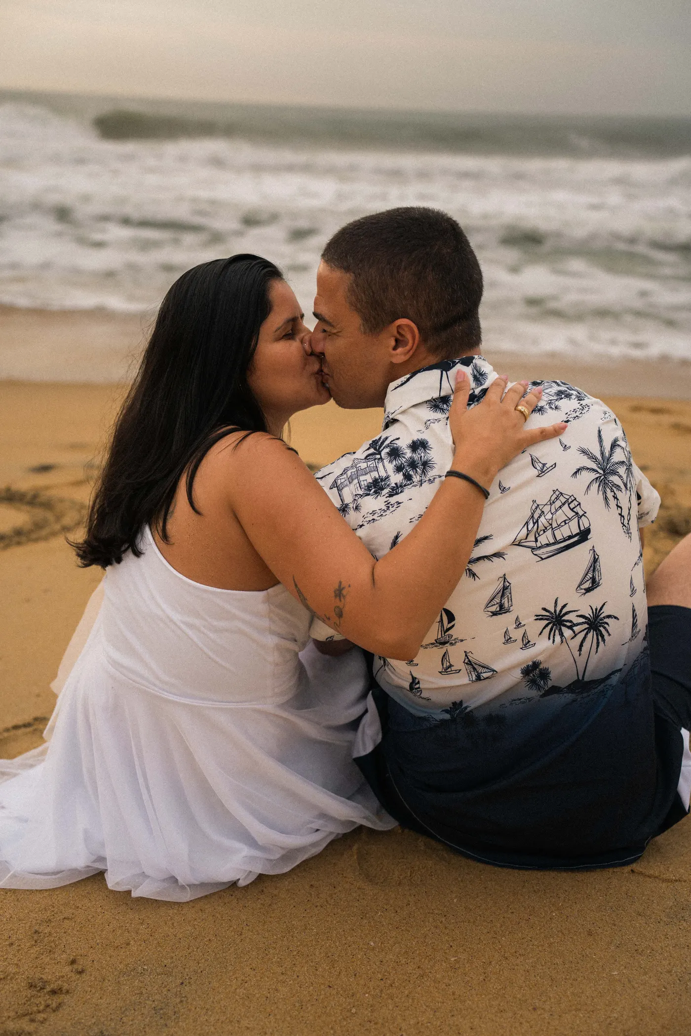 Noivos sentados na areia se beijando, com o mar ao fundo — foto autoral de Renan Life, Ubatuba