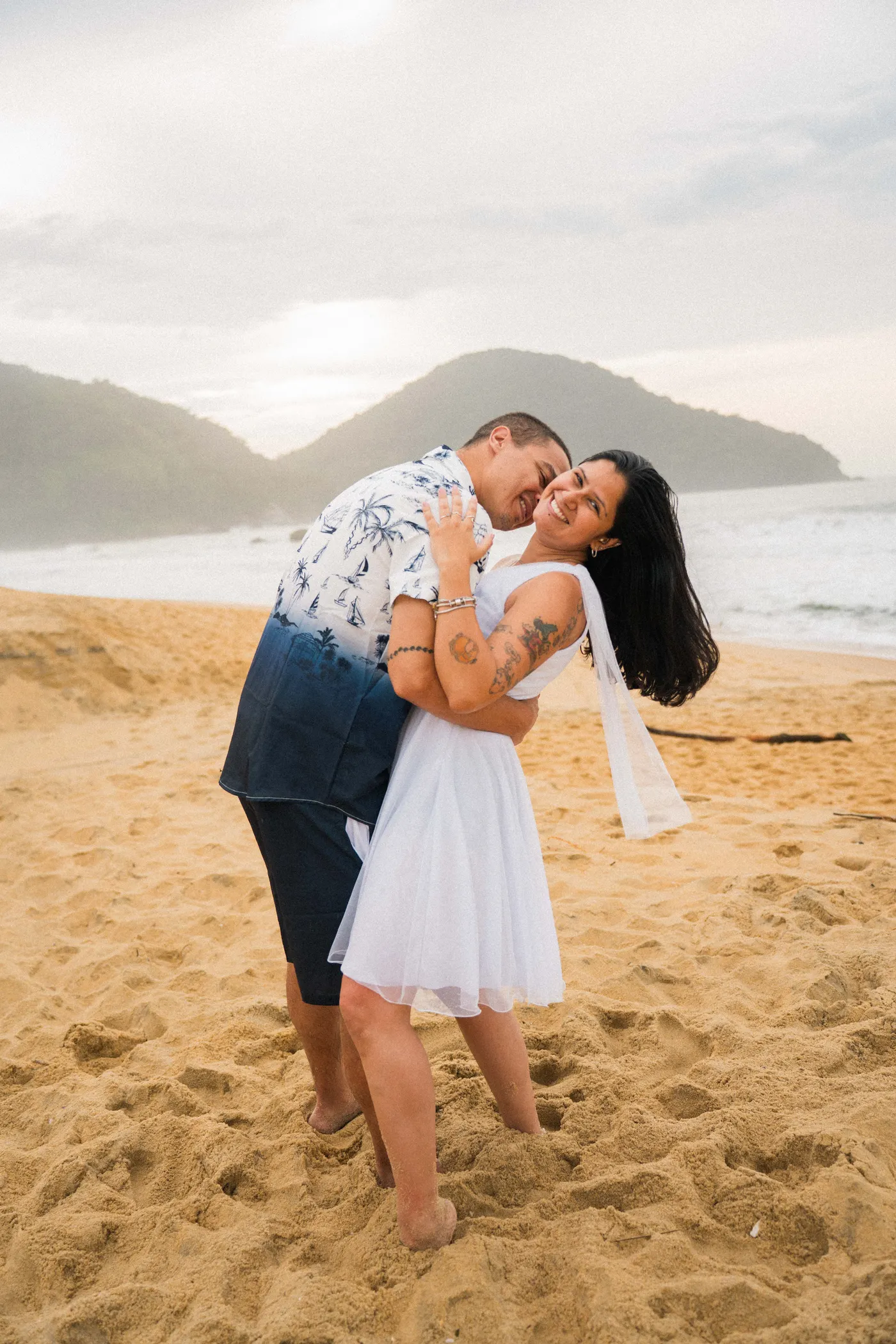 Noivo inclina a noiva num passo de dança, os dois rindo — foto autoral de Renan Life, Ubatuba