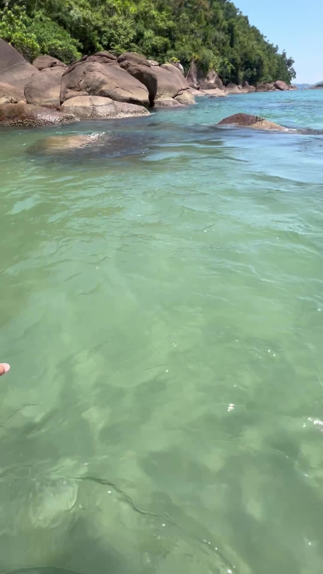 Mar calmo e cristalino com costeira de pedras ao fundo