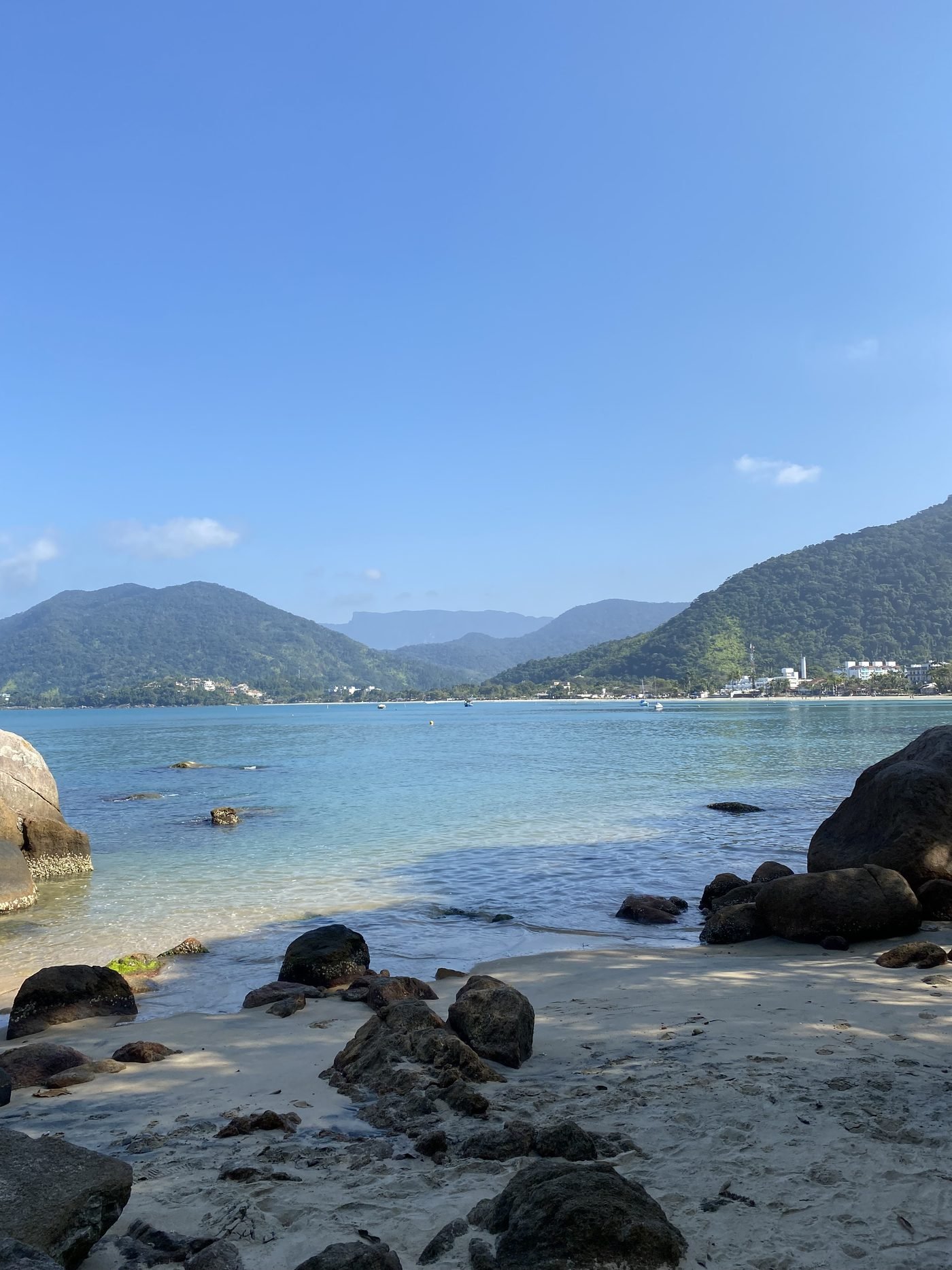 Areia e mar calmo na Praia da Enseada com a serra ao fundo