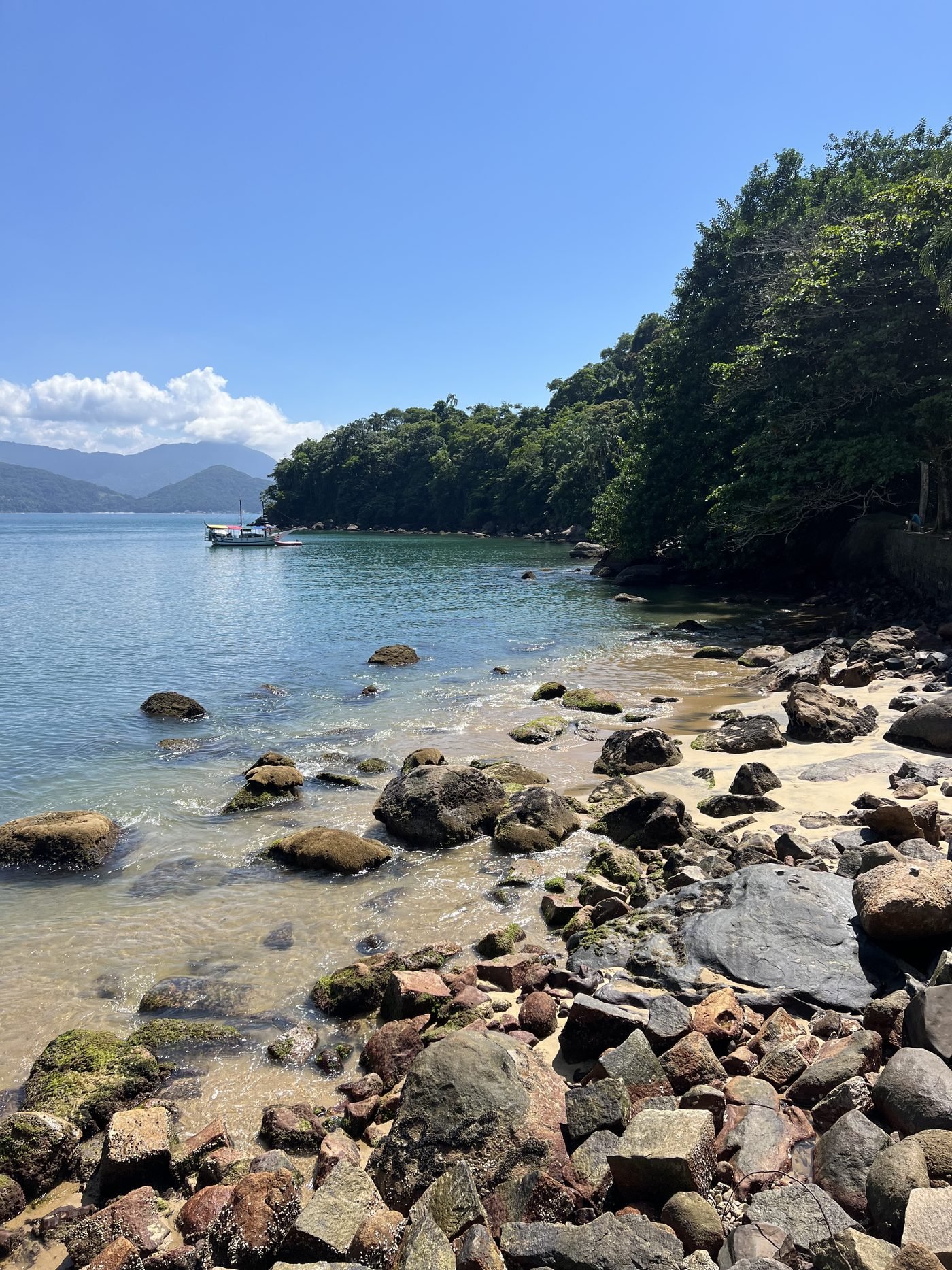 Prainha do Cais com pedras, mar calmo e mata ao fundo, perto do Centro de Ubatuba